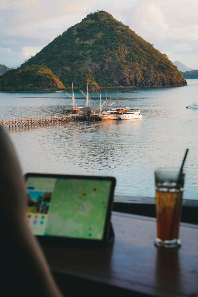 Meerblick, im Vordergrund arbeitet jemand an einem Tablet. Im Hintergrund eine Insel.