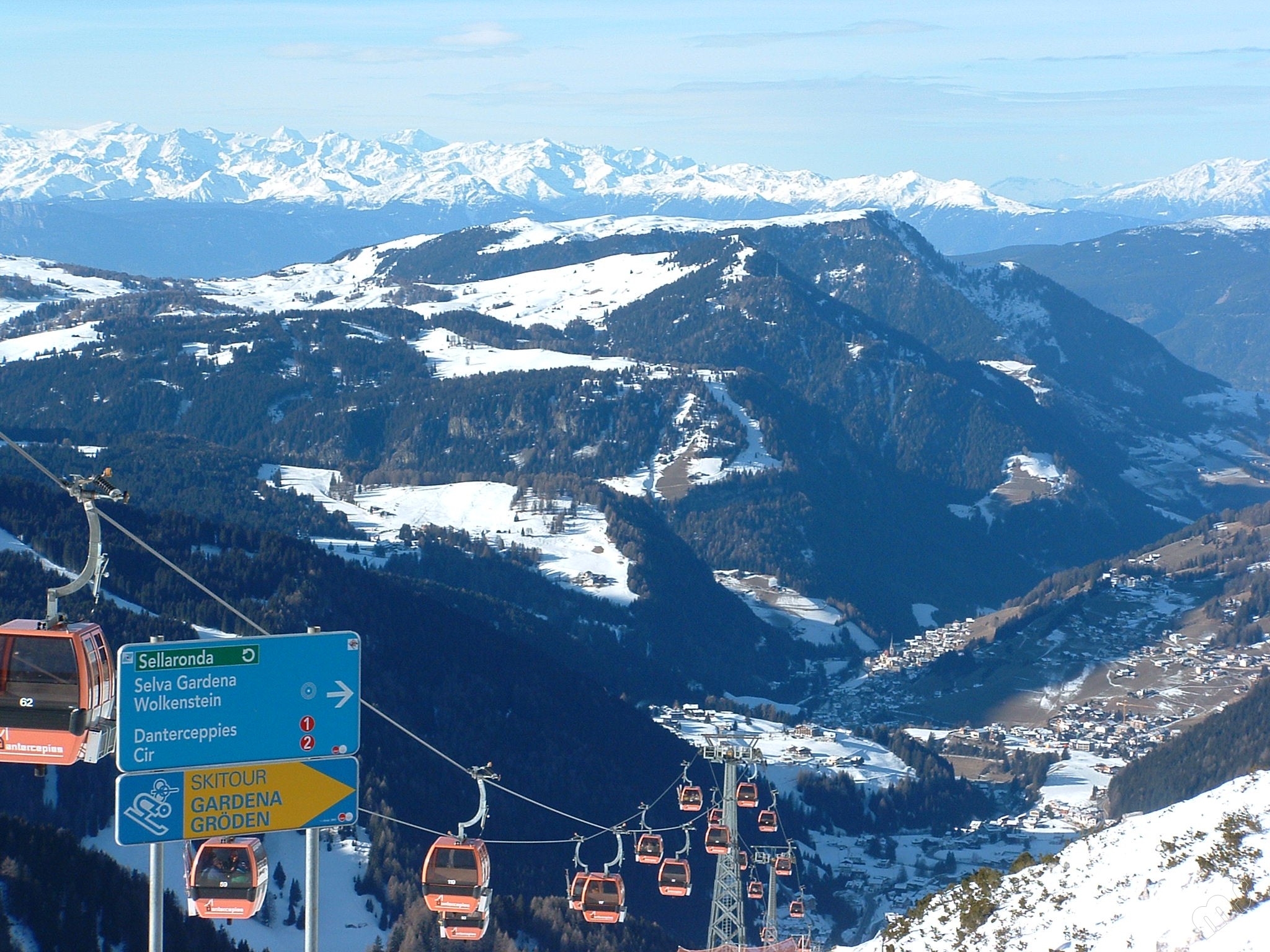 Ein Schild mit der Aufschrift "Sellarunde" vor dem Panorama eines Skigebiets