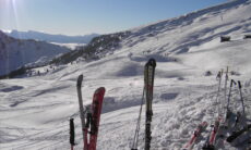 Ski stecken vor einem Bergpanorama aufrecht im Schnee